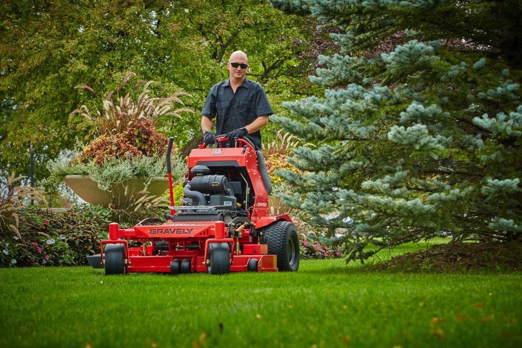 Showing gravely commercial lawn mower pro-stance stand on mower cutting grass by landscaper Abco Truck Equipment Toledo Ohio and Michigan