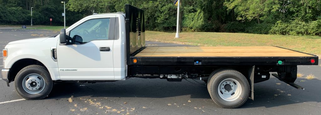 Showing black steel flatbed work truck body with yellow pine wood floor and buyers icc bumper on white chassis installed by Abco Truck Equipment Toledo Ohio and Michigan